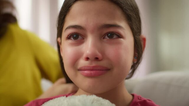 Close up suffering sad crying bad feeling Caucasian little girl kid daughter tears schoolgirl stress violence at home abuse mental health problems ignoring mother female woman calming comforting child