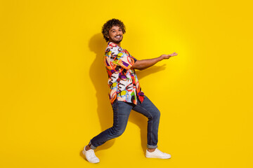 Full length portrait of nice young man hold empty space wear shirt isolated on yellow color background