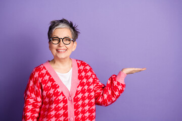 Photo portrait of lovely pensioner lady hold empty space dressed stylish red garment isolated on violet color background