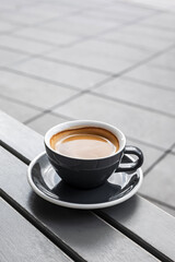 A cup of black coffee on the table of a city cafe or bakery terrace