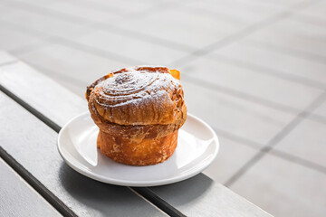 A cruffin on the plate on the table of a city cafe or bakery terrace