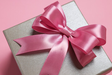 Gift box with bow on dusty pink background, closeup