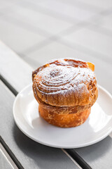 A cruffin on the plate on the table of a city cafe or bakery terrace