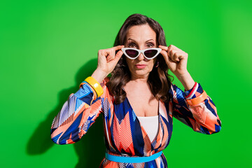 Photo of suspicious pretty lady dressed print outfiit dark eyewear empty space isolated green color background