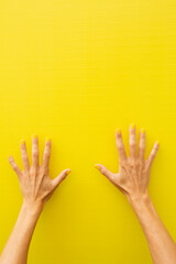 Woman's hands showing all ten fingers with yellow painted nails.