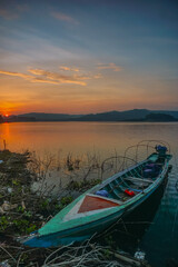 Fototapeta premium Lake boat at orange sunrise. Scenic sunrise background. Peaceful morning of Jatiluhur reservoir. 