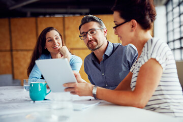 Employees, people and smile on tablet at office in meeting with teamwork, collaboration and ideas web designer. Business, coworking and happy in boardroom with clients for review on creative project