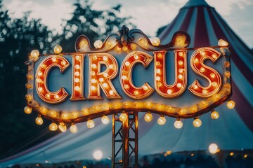 A sign which reads CIRCUS in retro light bulbs outside a big top circus tent in the evening, dusk or twilight. 
