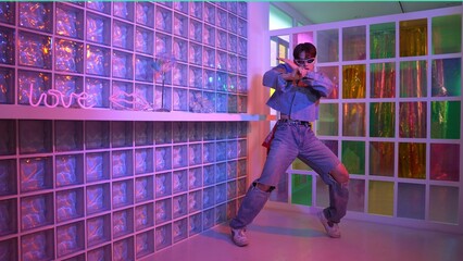 Asian performer with sun glasses moving freestyle dance while looking at camera at nightclub. Happy...