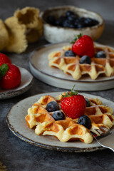 Belgian waffles with blueberries and strawberries on plates on the table