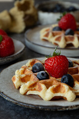 Belgian waffles with blueberries and strawberries on plates on the table