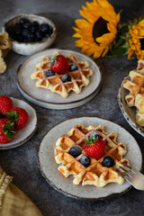 Belgian waffles with blueberries and strawberries on plates on the table