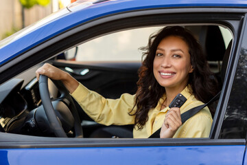 Successful happy woman showing keys of her own car and smiling at camera while sitting on driver's seat, buying brand car