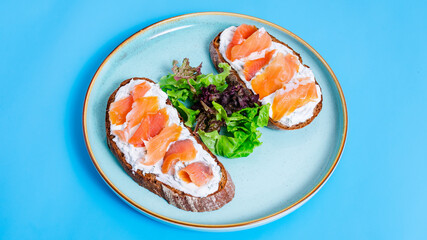 Two bruschettas with salmon and cheese in blue plate