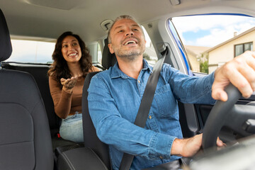 Positive woman passenger talking to cheerful taxi driver man, lady sitting on backseat. Easy transportation concept