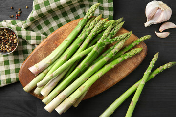 Fresh green asparagus stems and spices on gray wooden table, flat lay