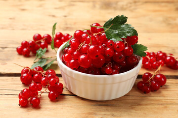 Fresh red currants and green leaves on wooden table, closeup