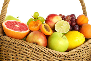 Many different fresh fruits in wicker basket isolated on white