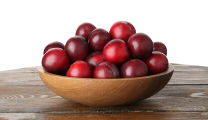 Fresh ripe plums in bowl on wooden table against white background