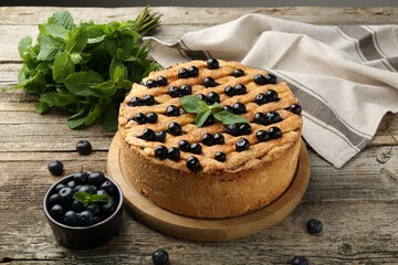 Delicious homemade blueberry pie with mint and fresh berries on wooden table