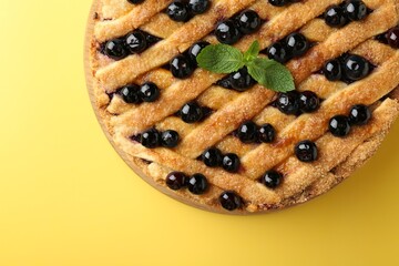 Delicious homemade blueberry pie with mint on yellow background, top view