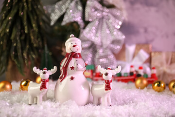 Funny snowman figure and deers on artificial snow
