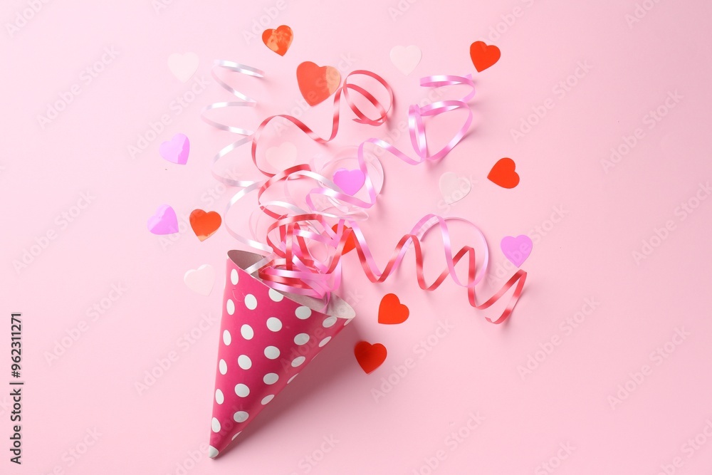 Wall mural Party hat with confetti and streamers on pink background, flat lay