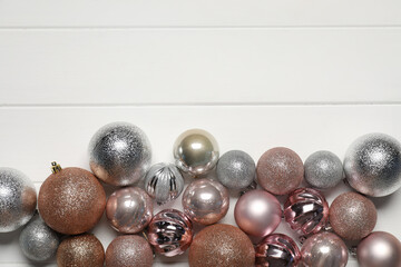 Different Christmas baubles on white wooden table, flat lay. Space for text