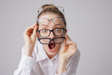 Surprised woman wearing multiple pairs of glasses with shocked expression, astigmatism concept