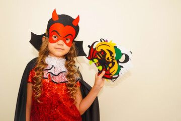 Unique child. Halloween. Girl in Halloween carnival mask. The child made handmade felt masks for Halloween. Girl prepared for Halloween celebration. Bat, pumpkin, witch, skull and devil masks