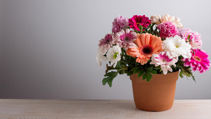 A Variety of Pink Flowers and Greenery in a Clay Pot with Copy Space