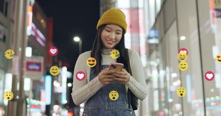 Social media, emoji and phone with Asian woman in city for algorithm, notification and connection. Icon, online review and comment with person for viral post, global message and dating app overlay - Powered by Adobe