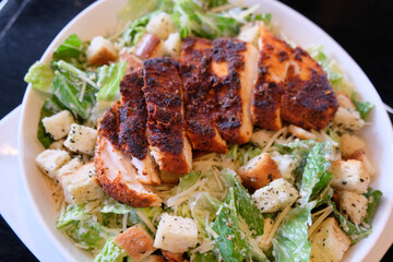 Caesar salad with blackened chicken, romaine lettuce, croutons, and parmesan cheese