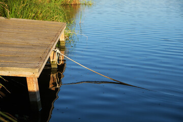 Fototapeta premium old pier over water, rope tied to pier, water striders on water