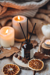 Concept of house decor, apartment seasonal fragrance. Thanksgiving. Autumn mood, cozy fall home atmosphere. Aroma diffuser, pumpkins, knitted warm sweaters, burning candles, dry leaves on wooden table
