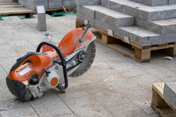 A concrete cutter rests beside neatly stacked stone blocks, showcasing tools of construction during...