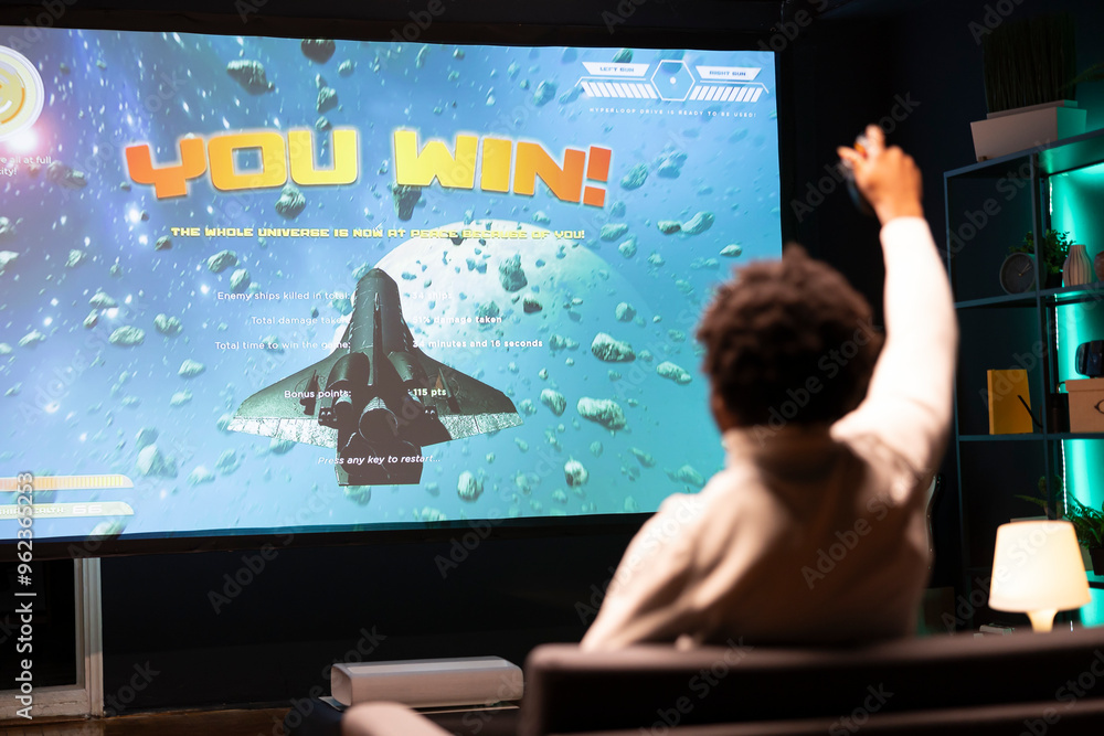 Wall mural man playing videogames on gaming console, celebrating victory. gamer excited after winning online mu