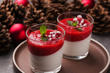 Two portion Panna cotta with strawberry sauce in glasses on a dark stone table. Christmas and New...