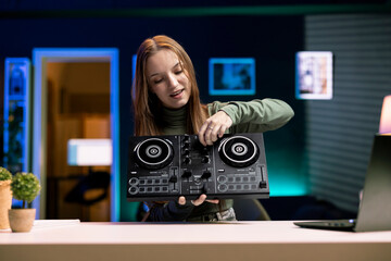 Cheerful young artist filming DJ mixing tutorial in home studio, showing examples of sampling on...