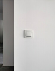 Electric double light switch on a white background, on a wall with plaster in a bright interior. Electricity and communications in the apartment and house. Technology, power supply and design