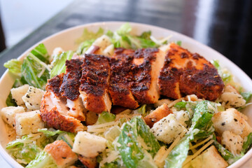 Blackened chicken Caesar salad with croutons, romaine lettuce, and parmesan cheese