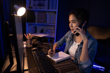 Young beautiful Asian creative woman calling on phone to customer or coworker informing strategy marketing creator plan while searching market analysis on pc at neon modern office at night. Stratagem.