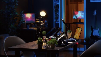 Panning shot of empty personal studio with high tech microphone, audio mixer and headphones used to...