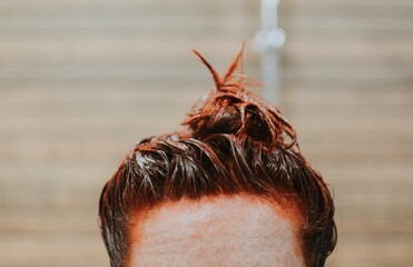 close-up of dyed red female hair in a bun on a brown background