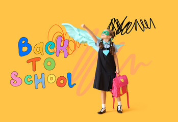 Happy schoolgirl dressed as superhero blackboard with backpack pointing at something on yellow background