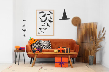 Interior of festive living room with brown sofa, Halloween decorations and gift boxes