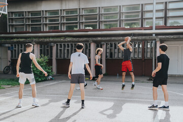 A group of friends engaged in a casual basketball game at an old neighborhood court, capturing the...