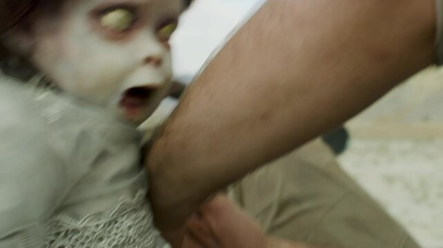 Creepy zombie baby trying to bite man's arm - close up