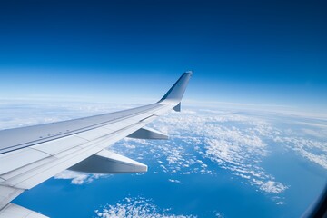 Fototapeta premium Airplane wing seen from window with view of clouds and blue sky.