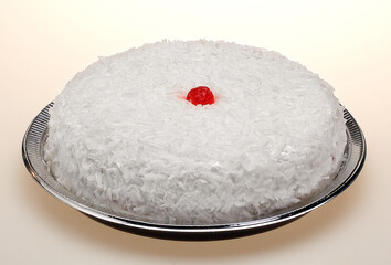 Coconut pie with frosting and a cherry.